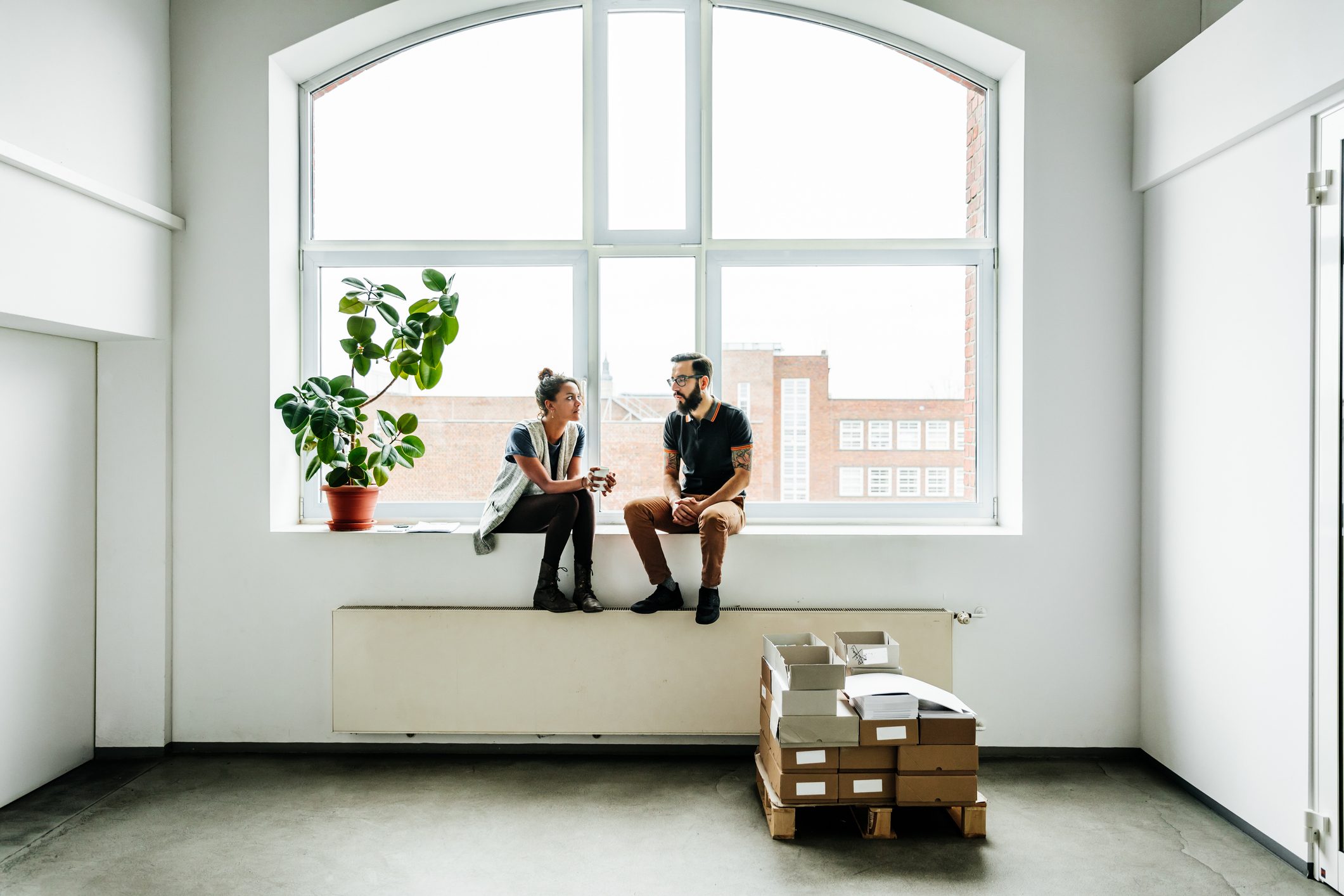 two people talking in empty room by the window