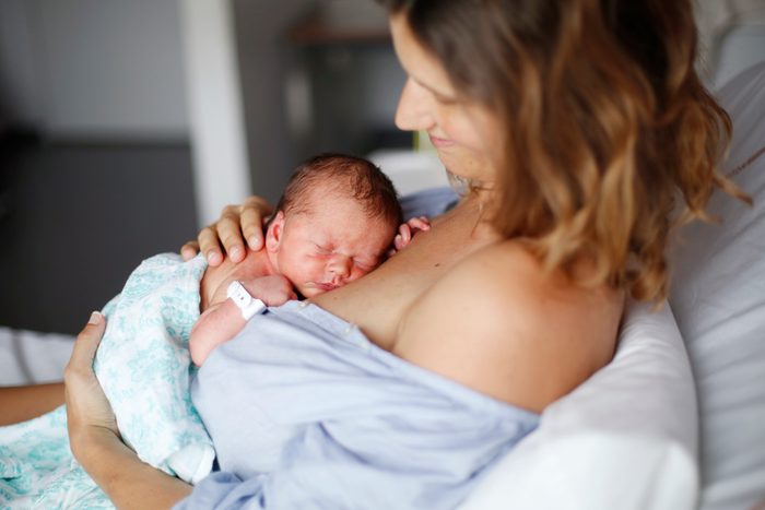 woman in hospital bed holding her newborn baby