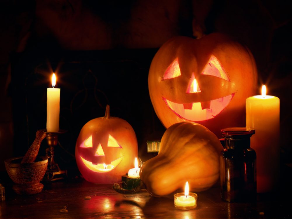 Halloween Jack O' Lantern pumpkin head stacked at Halloween night with burning candles on black background.