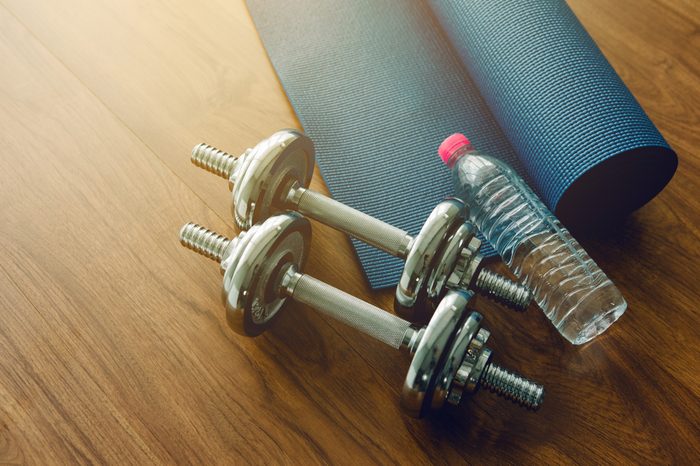 Pair of dumbbells, blue yoga mat, and bottle of water