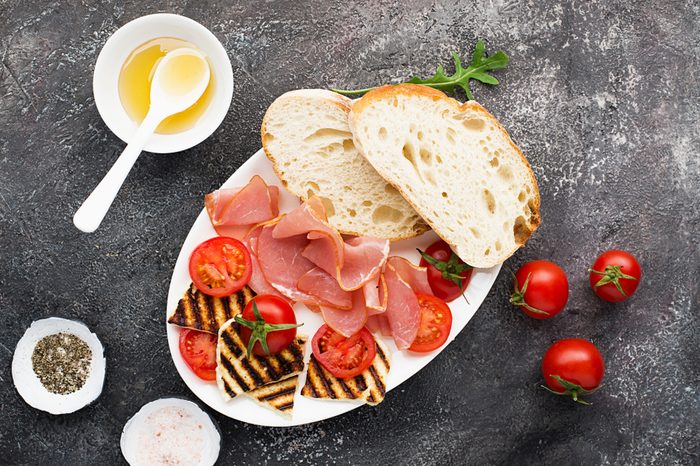 Halloumi cheese with bruschetta, tomatoes, prosciutto, honey, pine nuts on a plate