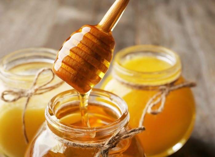Pouring aromatic honey into jar, closeup