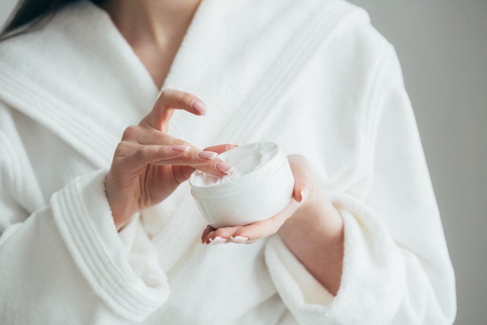 woman's hands holding a jar of beauty cream