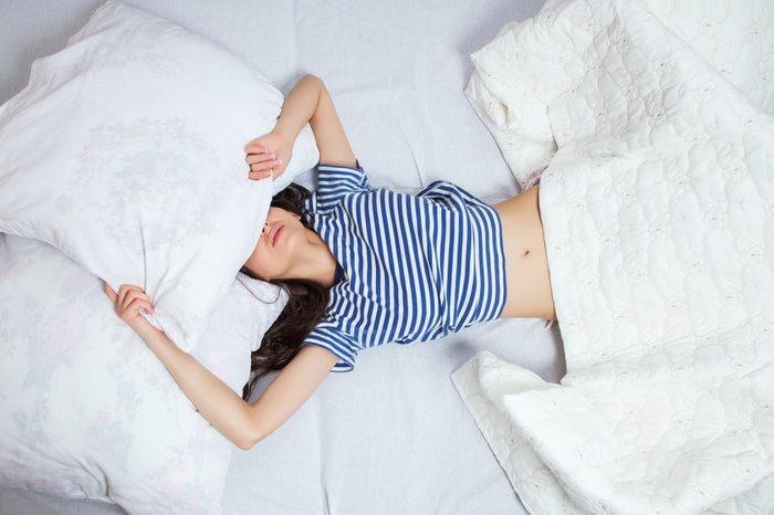 Girl sleeping on her back in bed with white sheets