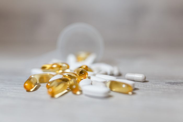 Plastic scoop on the table, vitamins, omega 3 pills on a wooden background