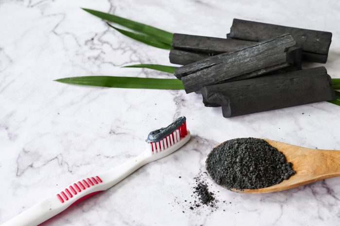 Toothbrush with charcoal toothpaste, spoon of charcoal powder, and charcoal