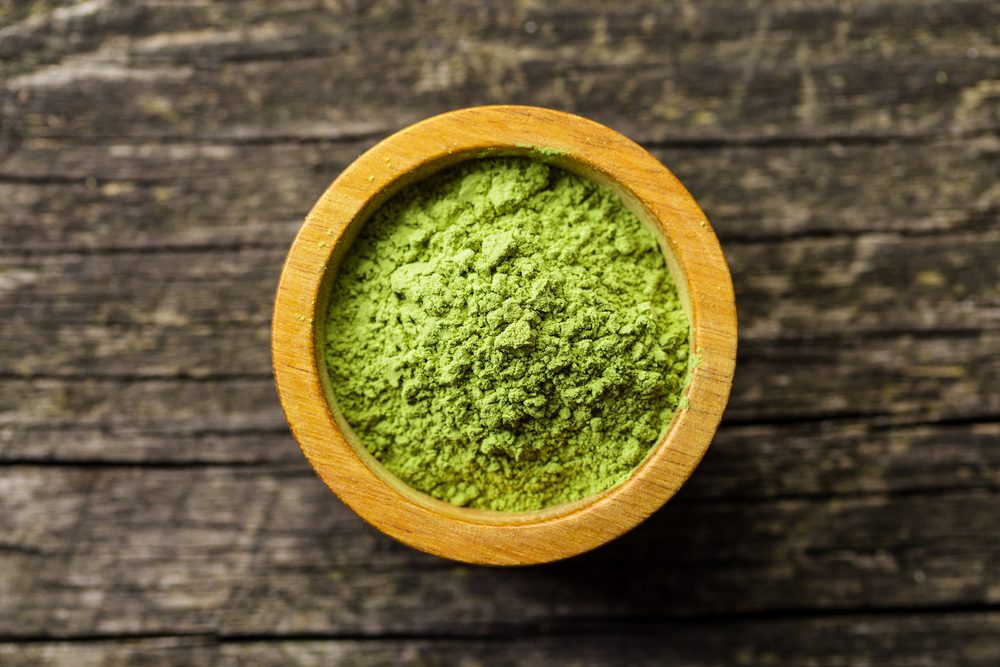 Green matcha tea powder in bowl. Top view.