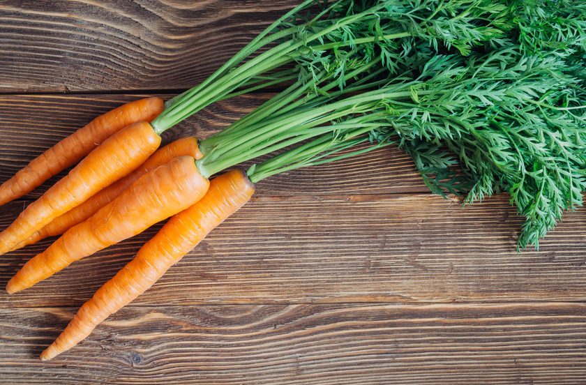 Close up of fresh carrot on rustic wooden background, top view