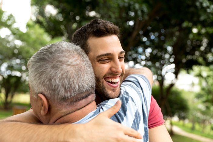 Adult son hugging his senior dad