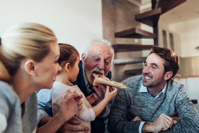 Three generation family eating pizza together