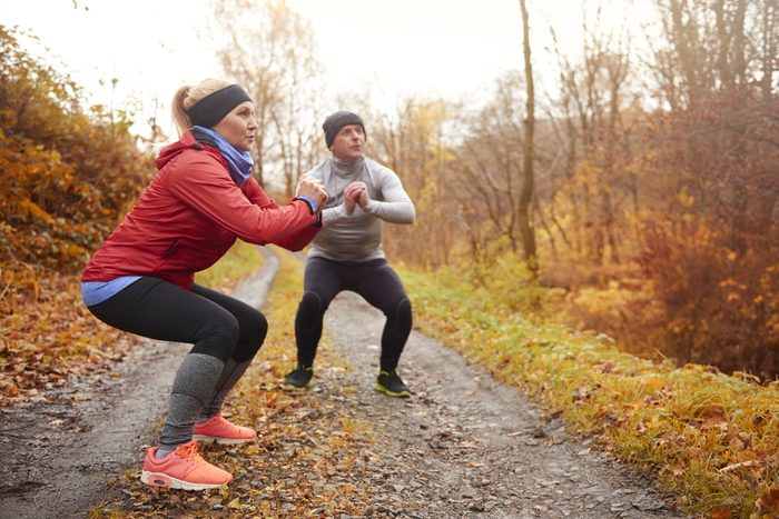 Couple doing squats and exercise outside