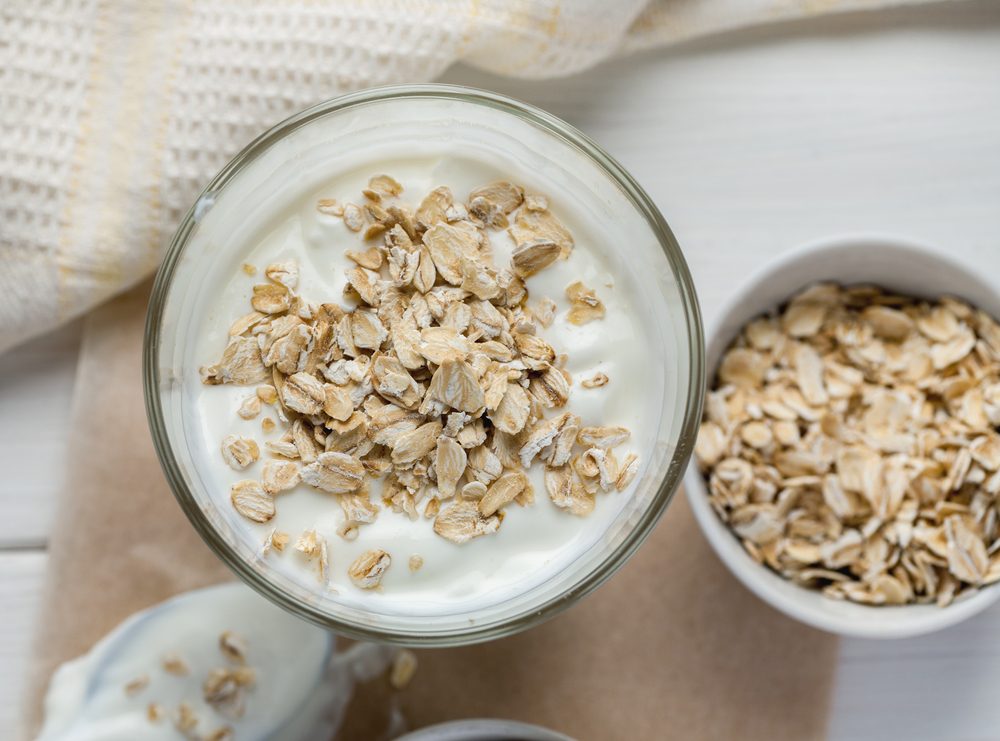 Yogurt with oat flakes on a wooden table, top view