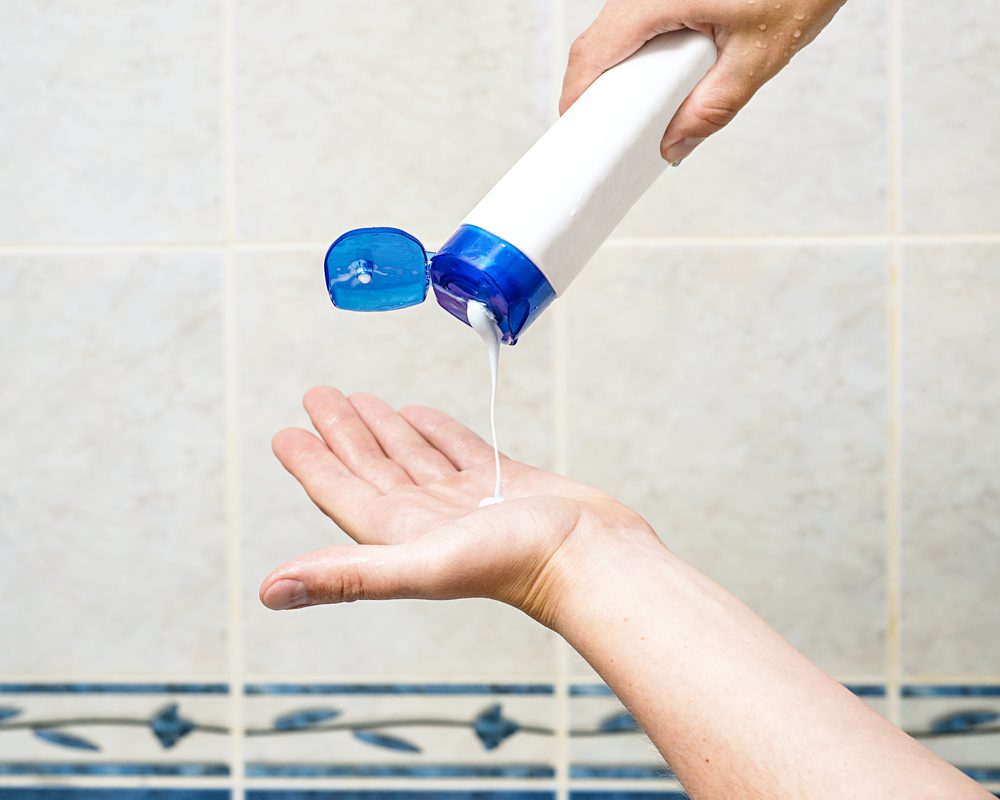 man is pouring shampoo on his hand, shower gel on hand, man hand holding bottle with shampoo and squeezing shampoo for hair from tube