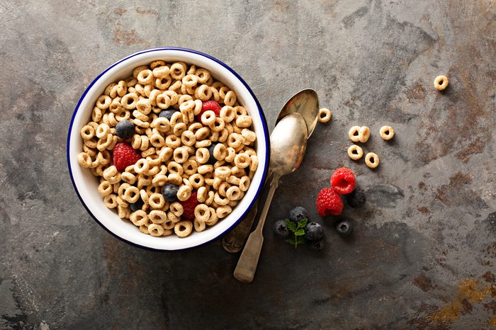 Healthy cold cereal with raspberry and blueberry in a bowl, quick breakfast or snack overhead shot