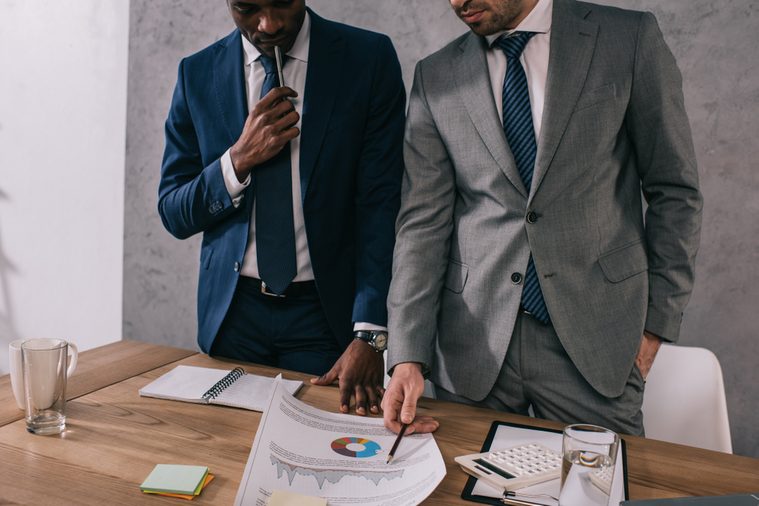 businessmen pointing to project on table