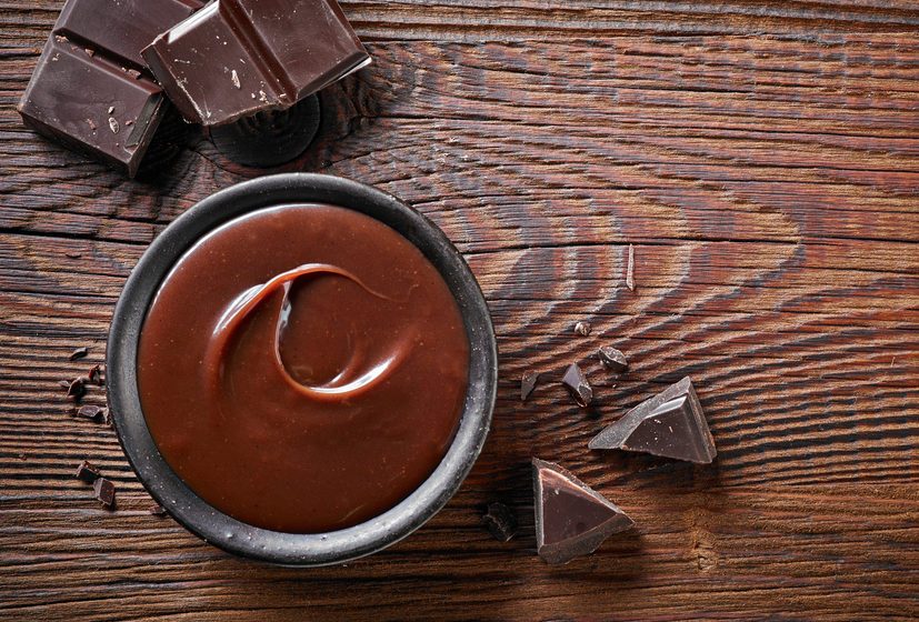Chocolate cream and chocolate pieces on wooden table