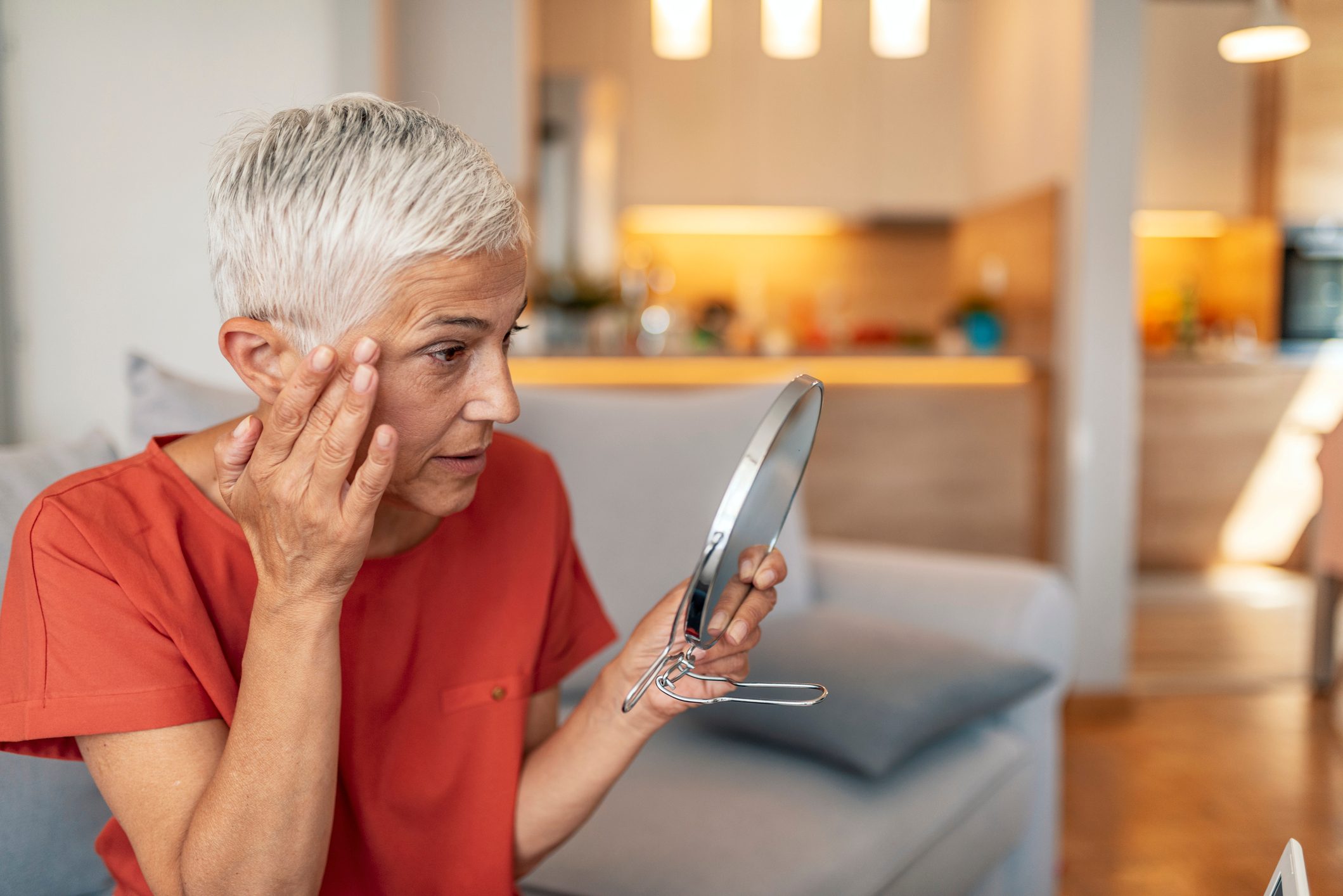 mature woman looking at her face in mirror