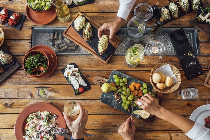 From above photo of hands of unrecognisable people at lunch table.