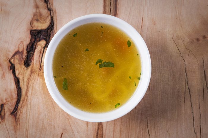 Chicken soup on a rustic wooden table, top view