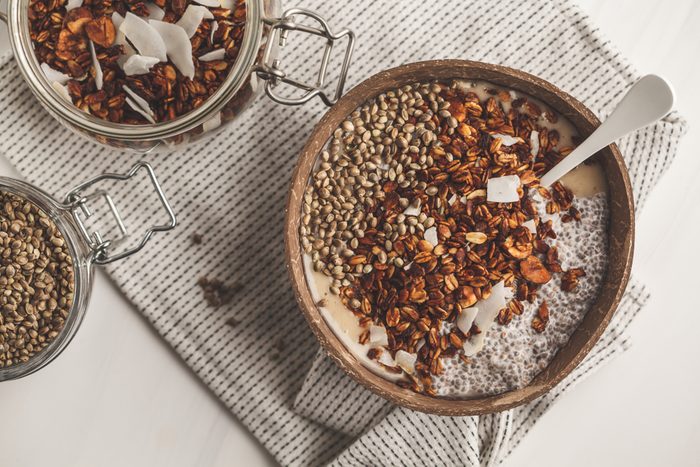 Smoothie bowl with granola, chia pudding and hemp seeds in coconut shell bowl, top view.