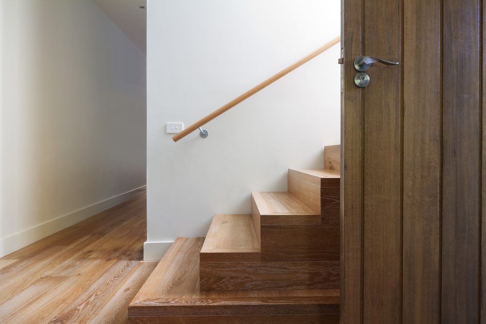 Modern staircase of oak wood beside front door in contemporary home horizontal