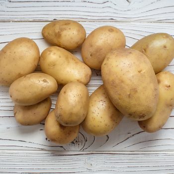 Young potatoes on white wooden background, view from above