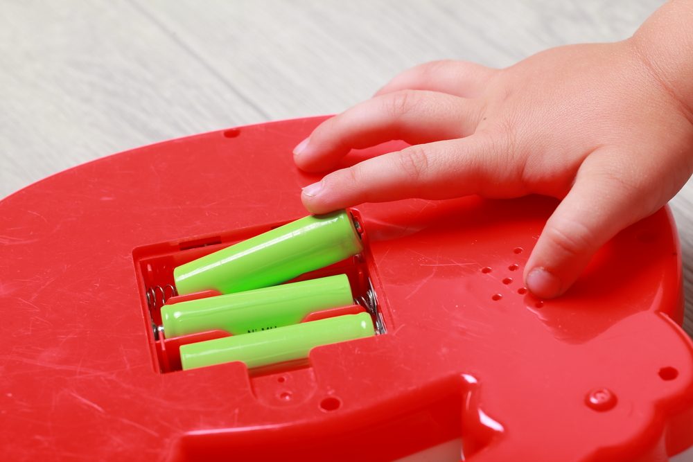 hand the child put the batteries in the red toy