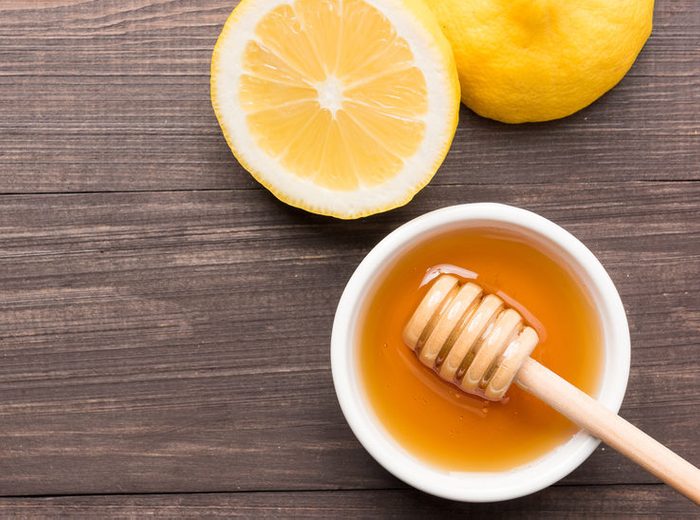 Bowl of sweet honey and lemons on wooden table.