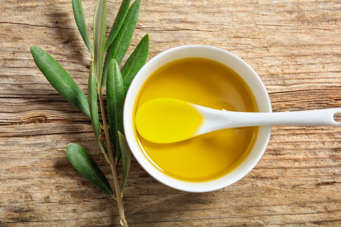 Olive oil and olive twig on a wooden surface