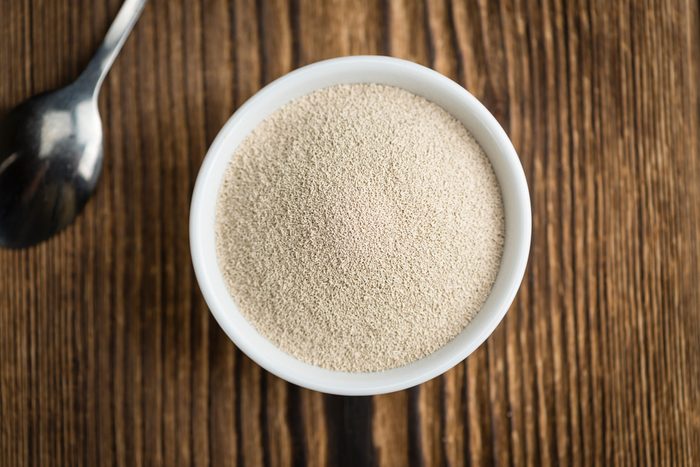 Bowl with dried Yeast (selective focus) on wooden background