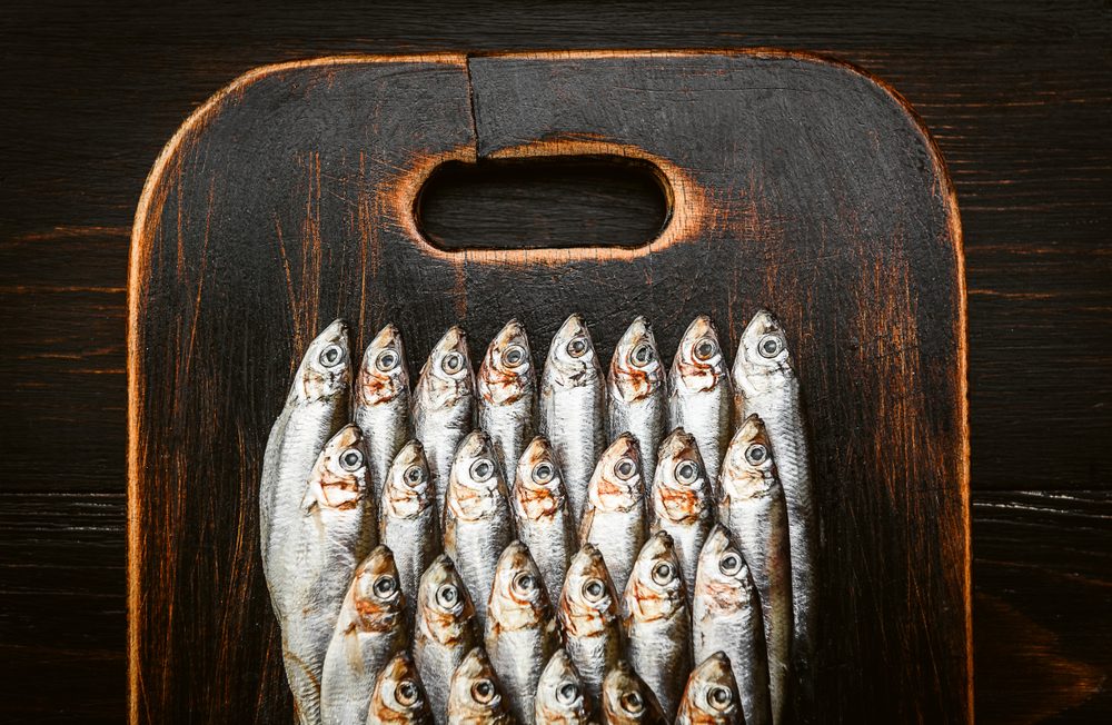 fresh raw fish anchovy and sprat on a wooden surface