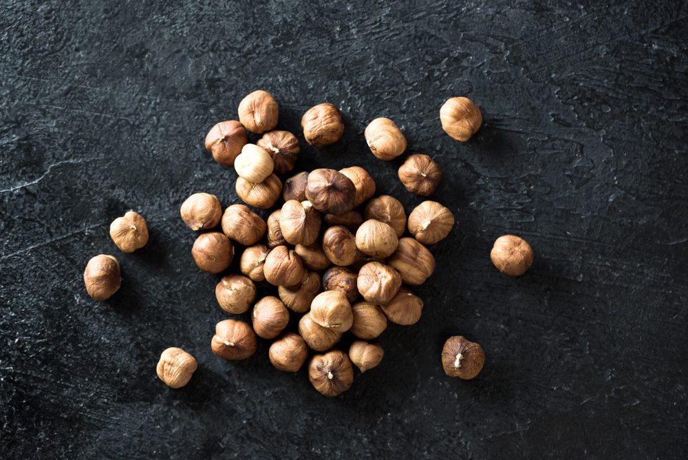 Organic Hazelnuts. Hazelnuts on black stone background, top view, copy space.