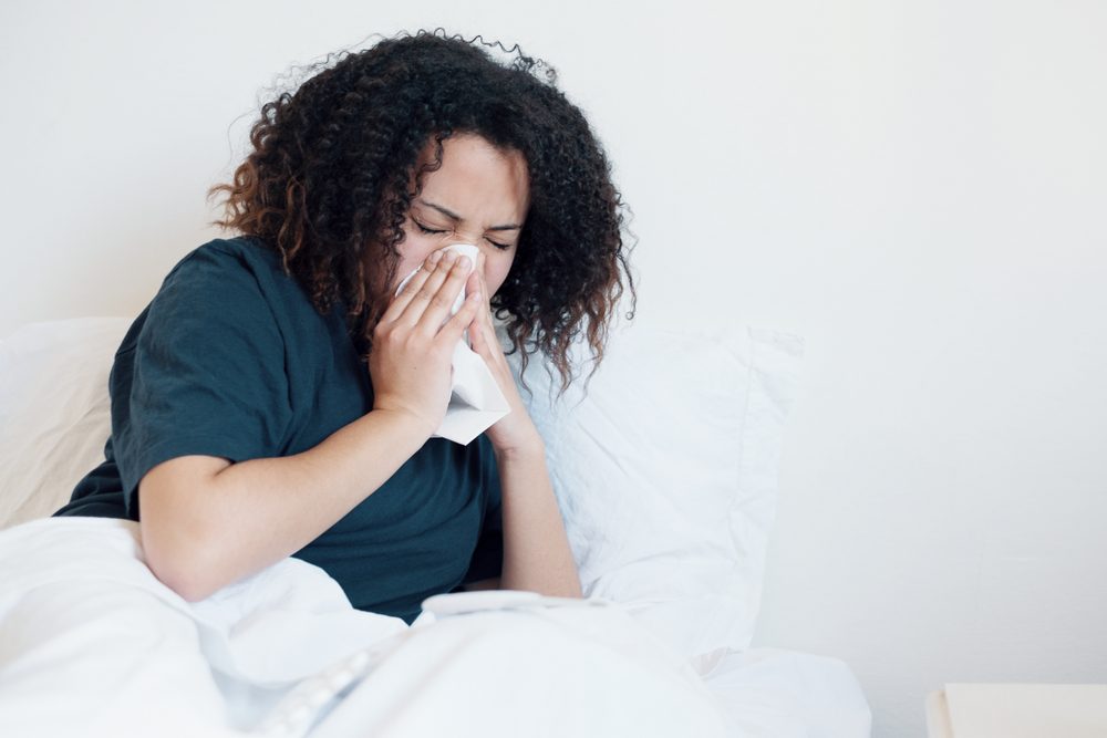 woman in bed, blowing her nose