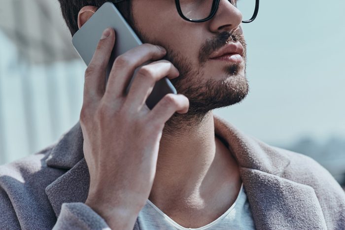 On the phone. Close-up of young modern man talking on the smart phone while standing outdoors
