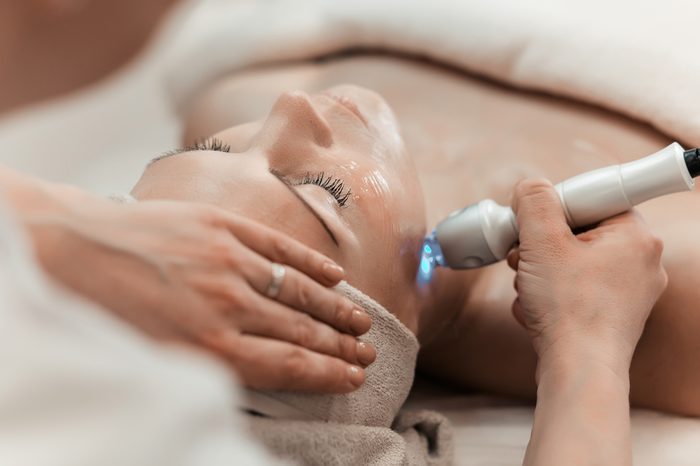 Woman getting laser and ultrasound face treatment in medical spa center, skin rejuvenation concept