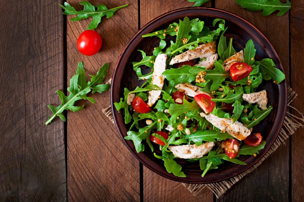 Fresh salad with chicken breast, arugula and tomato. Top view