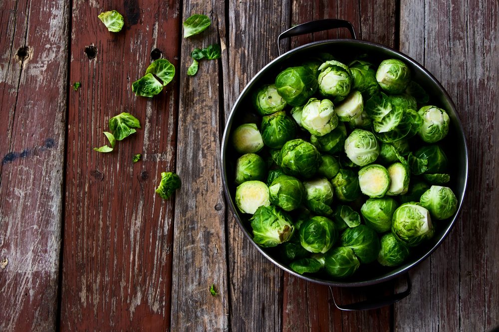 Fresh brussel sprouts over rustic wooden texture. Top view.