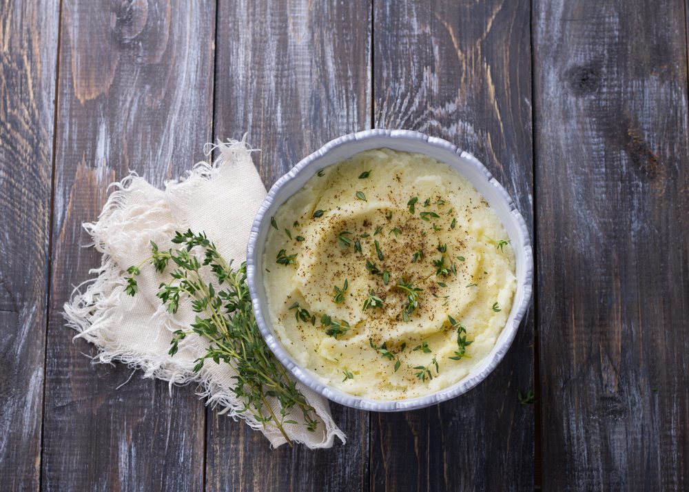 Cauliflower puree with olive oil, spices and thyme on a wooden table. Healthy vegetarian food. Rustic style, selective focus