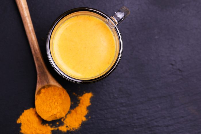 Traditional Indian cuisine. Turmeric milk with cinnamon, saffron, cardamom and turmeric on black slate background. Copyspace, top view, flatlay