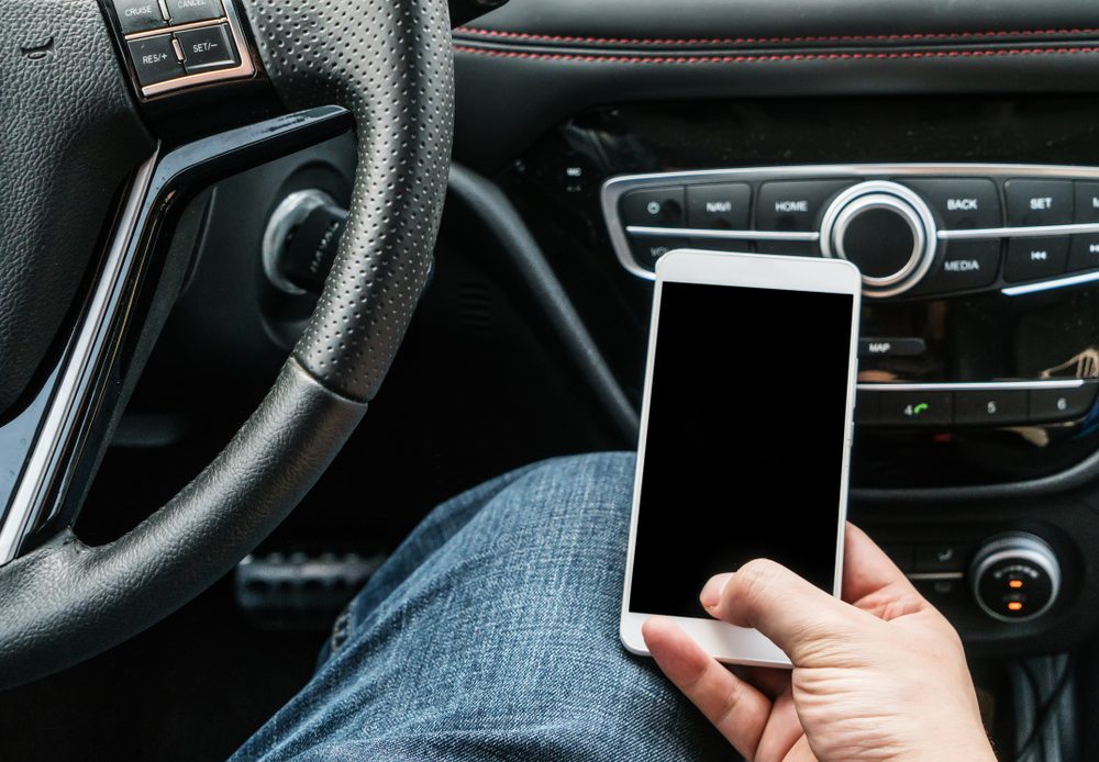 Shot of a handsome man using mobile phone while driving.