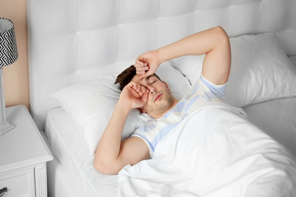 Young man rubbing his eyes in the morning