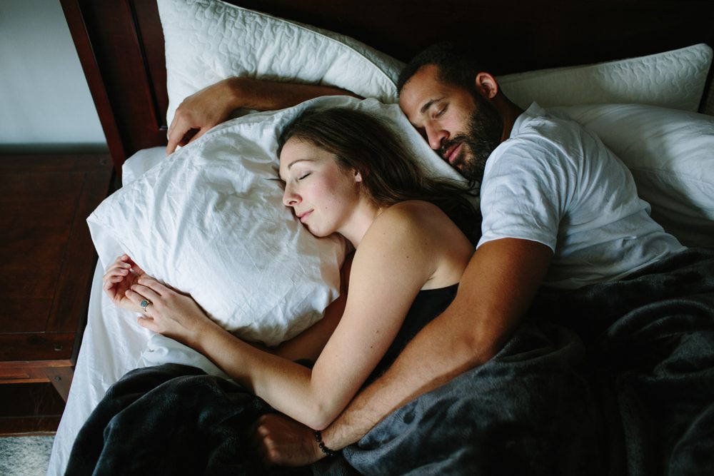 Black and white couple sleeping and holding each other in bed
