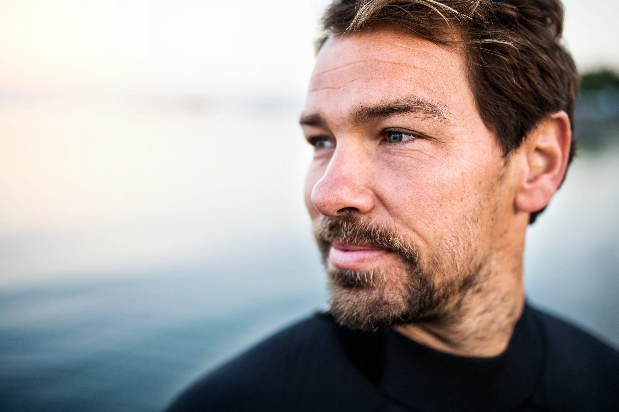 man with beard looking off into distance at the beach