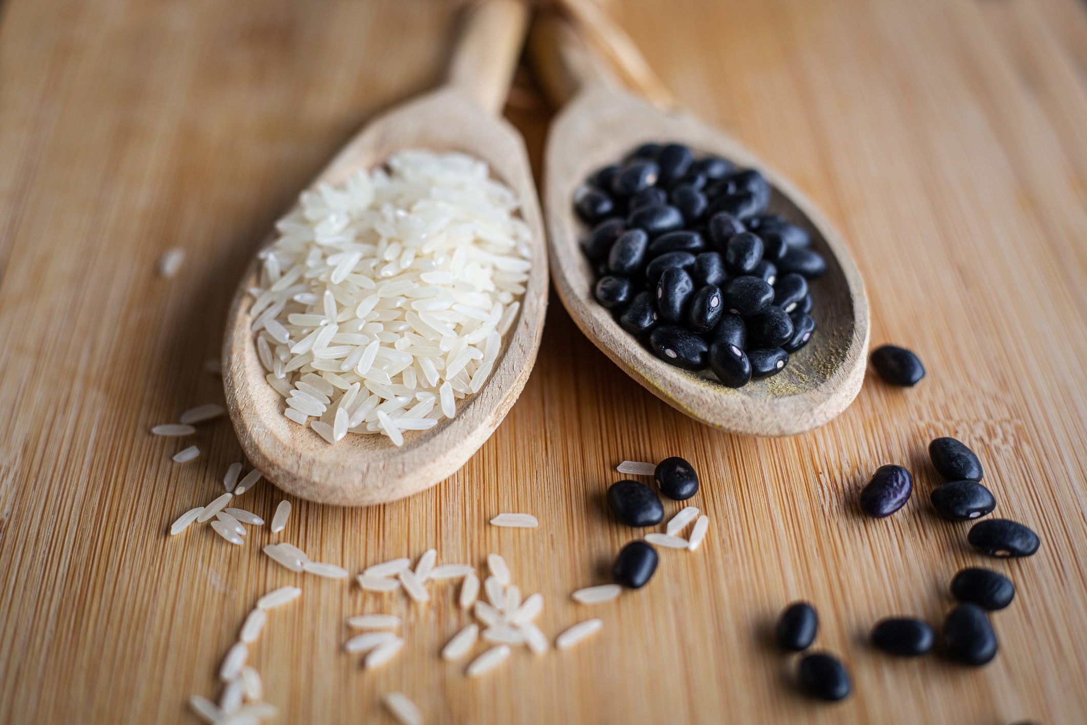 uncooked rice and beans in wooden spoons