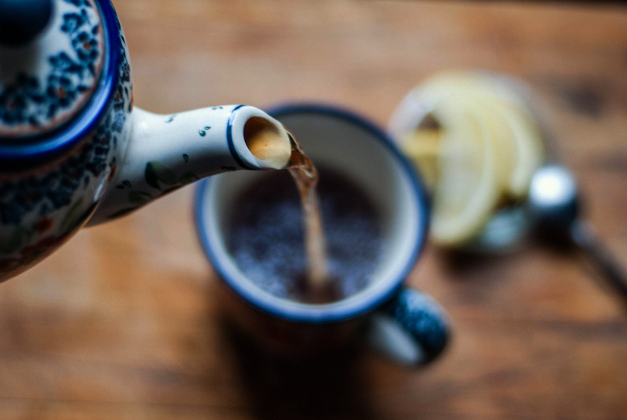 close up of tea kettle pouring tea into tea cup