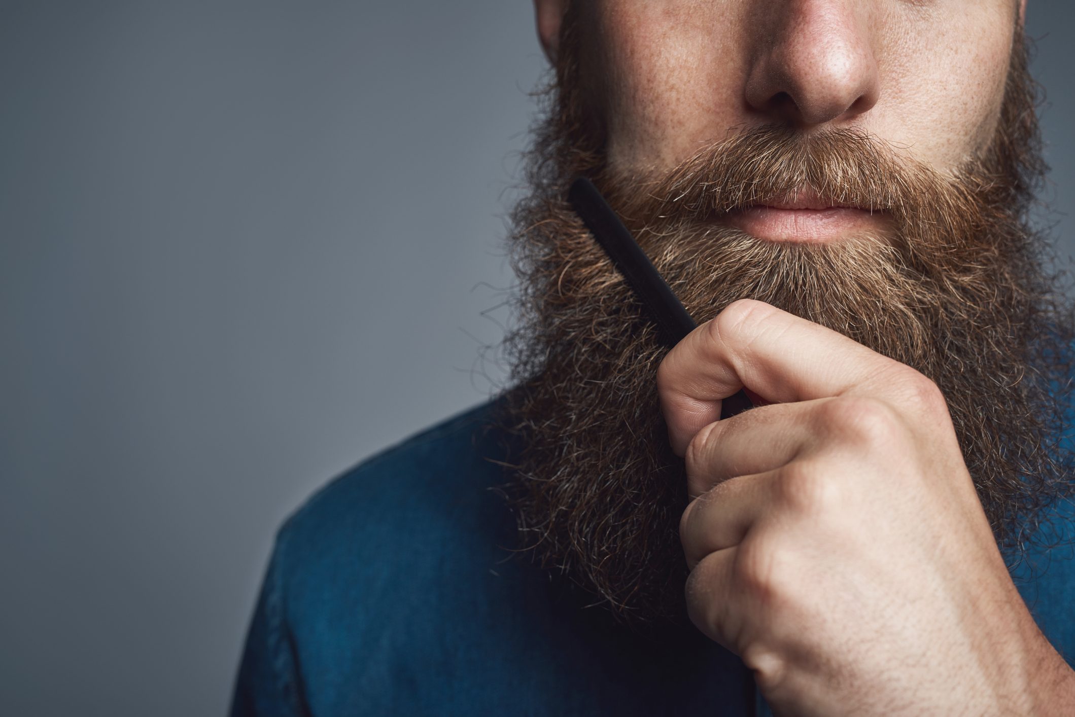 close up of young man brushing his beard
