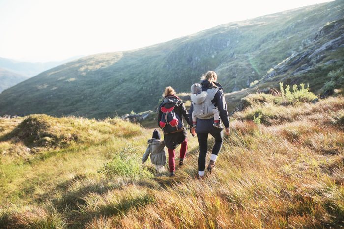family hiking outside mountains in the background