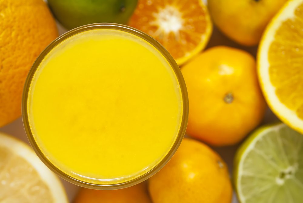 glass of orange juice surrounded by citrus fruits