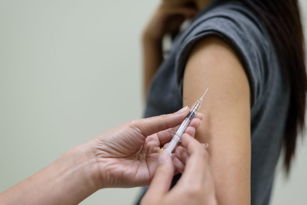 Close up doctor's hand injecting for vaccination in the shoulder woman patient.Vaccine for protection concept.