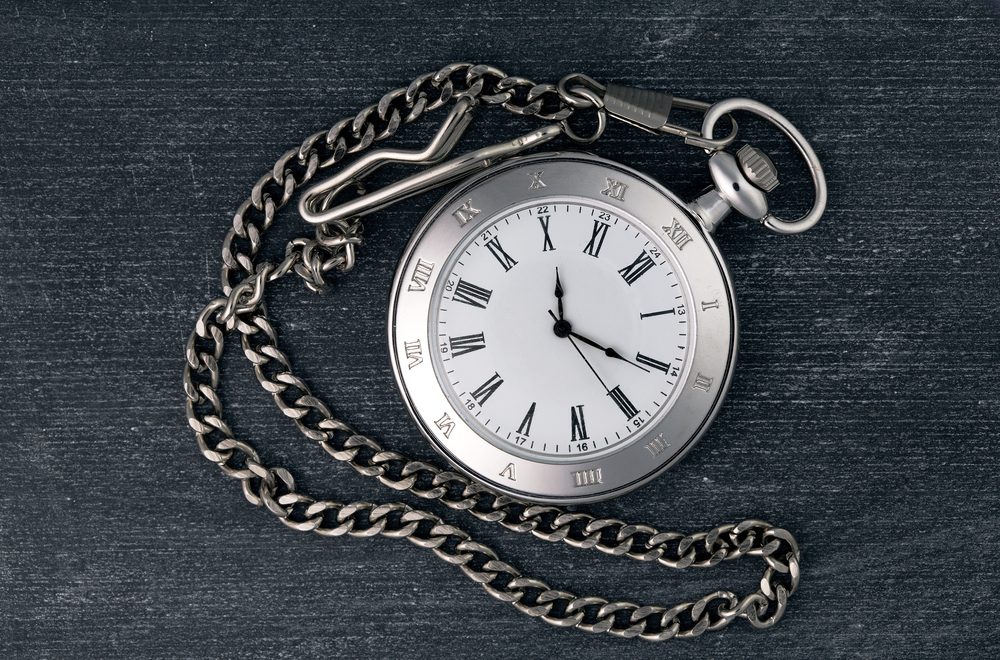 Shiny silver chain watch on a black chalkboard background